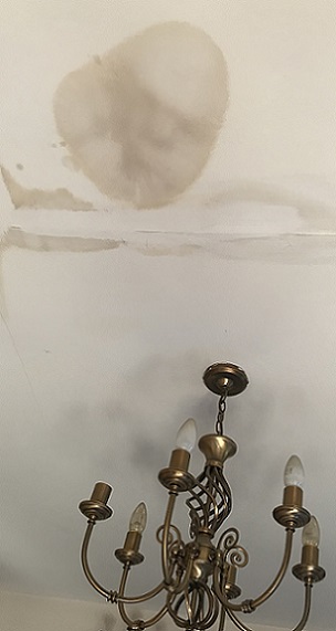 Una marca de agua de aspecto desagradable en un techo causada por una ducha que gotea arriba