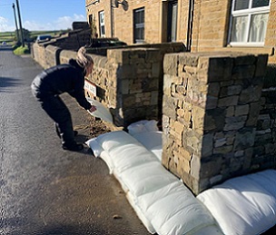 Lucy Bailey from Environmental Defence Systems Ltd placing a FloodSax in place at Lewyn Clegg's home