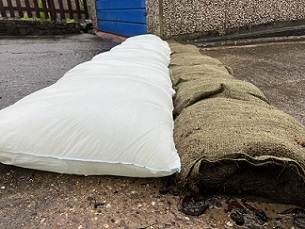 A line of FloodSax alternative sandbags next to a row of old-style sandbags